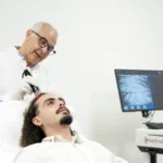 Traitement chute de cheveux : Un dermatologue applique la Luminothérapie LED rouge sur le cuir chevelu d'un patient pour stimuler la repousse des cheveux.