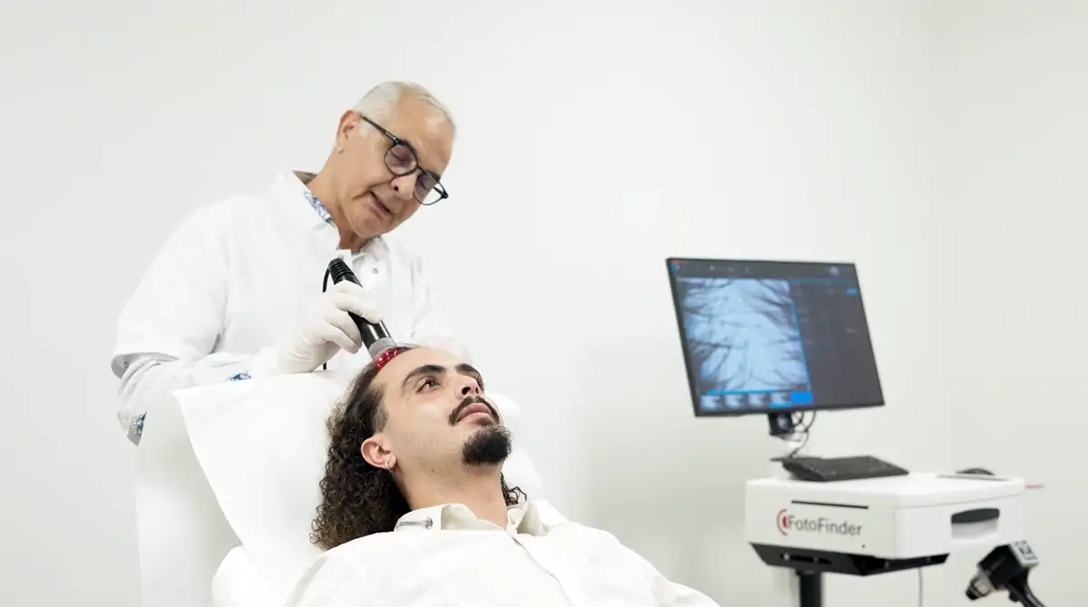 Traitement chute de cheveux : Un dermatologue applique la Luminothérapie LED rouge sur le cuir chevelu d'un patient pour stimuler la repousse des cheveux.