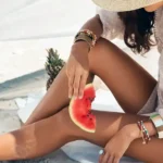 Femme à la plage avec une peau lisse après une séance d'épilation laser en été.