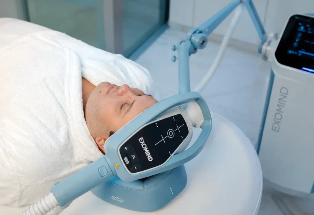 Gros plan sur l'applicateur de l'appareil ExoMind positionné sur la zone crânienne d'un patient pour un traitement sans aiguille ni douleur du stress.