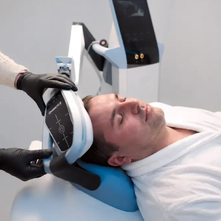 Praticien appliquant le dispositif de stimulation cérébrale ExoMind sur un patient allongé pour un soin de neuro-esthétique.