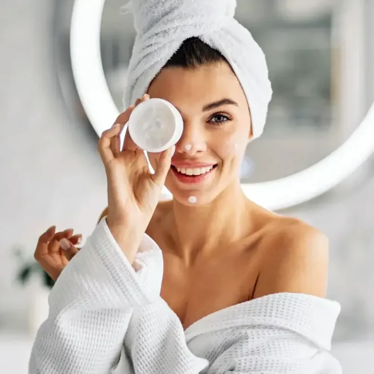 Femme appliquant une crème hydratante dans le cadre de sa routine après soin esthétique.